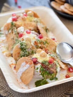 Papdi chaat arranged on a plate drizzled with green chutney